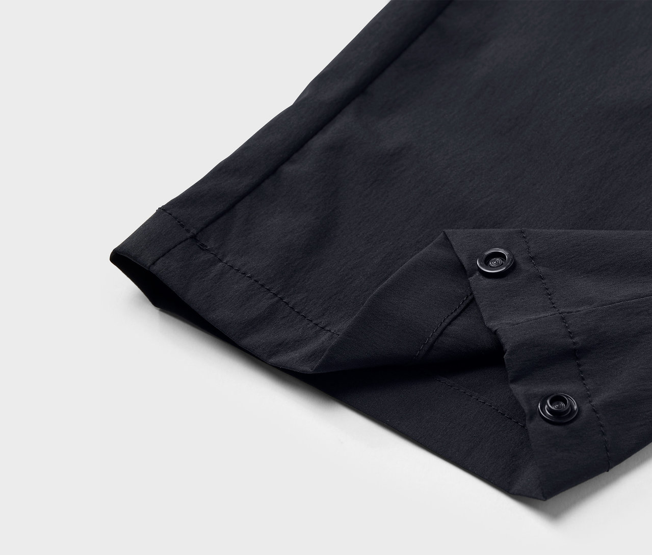 Detailaufnahme einer schwarzen Funktionshose mit Druckknopfverschluss.