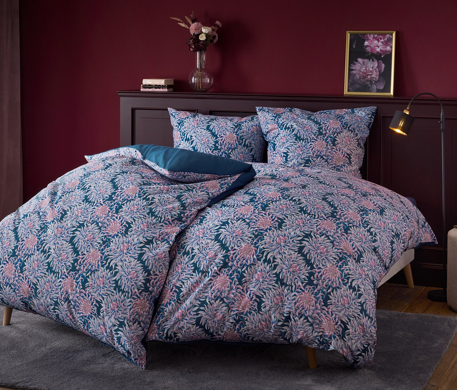 Blumige Bettwäsche auf einem Bett mit dunklem Holzkopfteil.