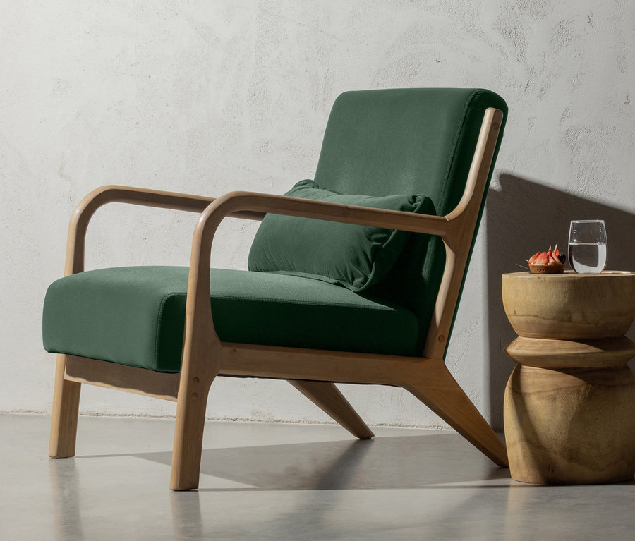 Grüner Sessel mit Holzrahmen und Kissen, daneben ein Woood Hocker »Bikkel«, Holz naturfarben, mit Getränk.