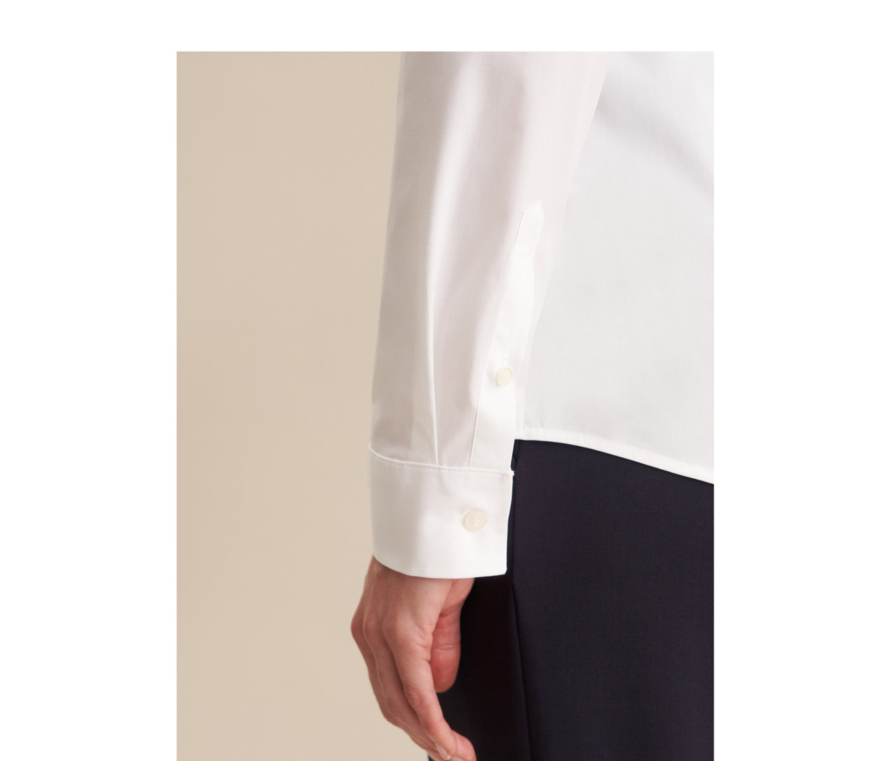 Nahaufnahme einer Person in einer weißen Seidensticker Slimfit Bluse mit geknöpften Manschetten und dunkler Hose. Eine Hand ist sichtbar.