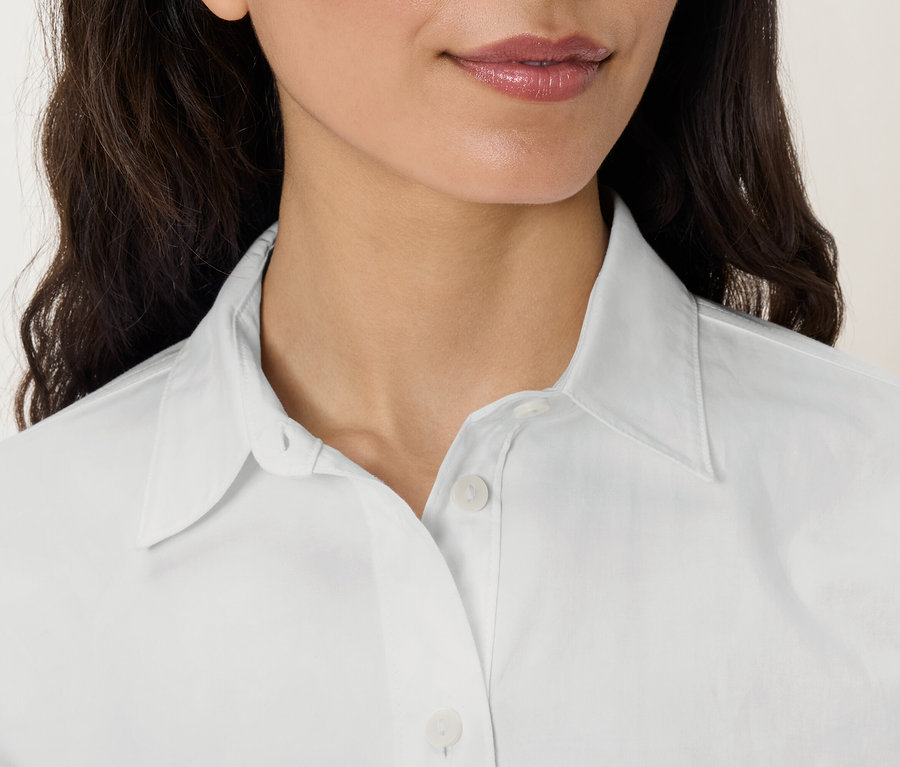 Detailaufnahme vom Gesicht und Oberkörper einer Frau in einem weißen Hemd mit Kragen.