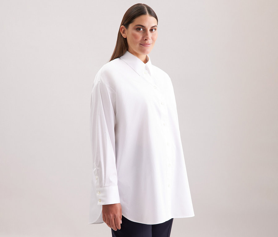 Frau trägt eine weiße Seidensticker Oversize Longbluse.