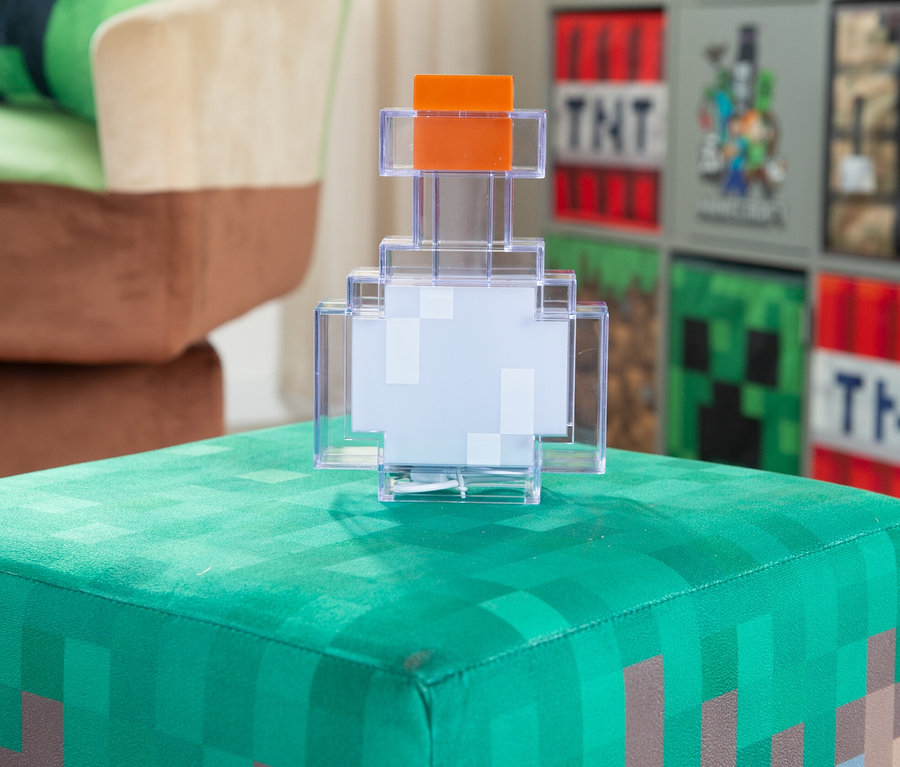 Eine MINECRAFT LED Dekoleuchte, Potion steht auf einem grünen Hocker mit Gras- und Erdmotiv.