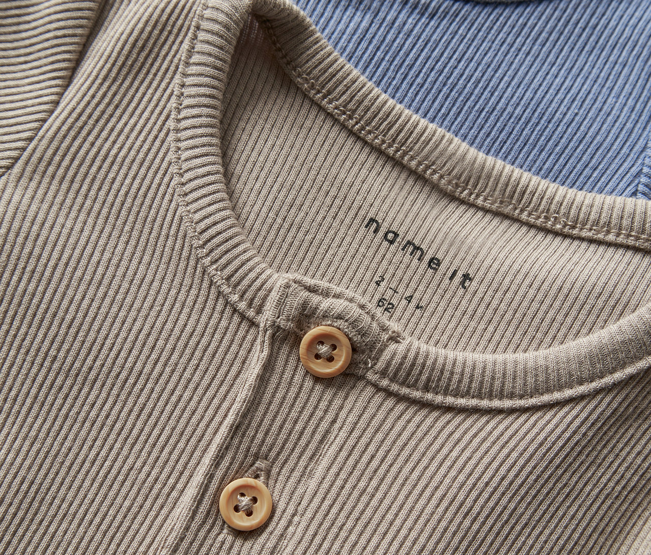 Nahaufnahme von zwei Baby-Bodys von NAME IT, troposphere, mit Knöpfen.