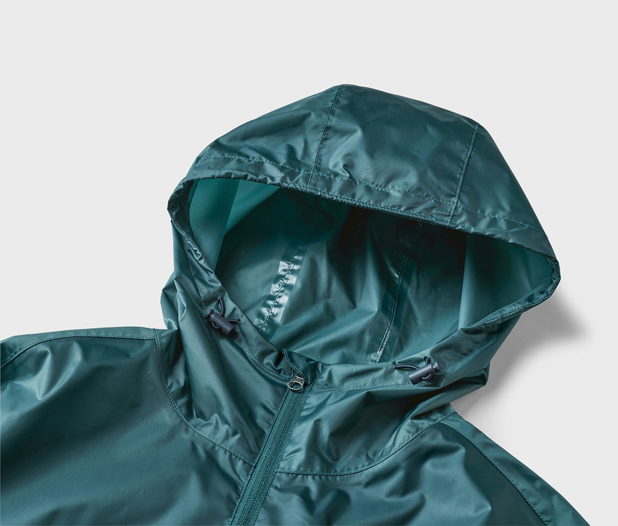 Nahaufnahme einer dunkelgrünen Regenjacke mit Kapuze und Reißverschluss vor neutralem Hintergrund.