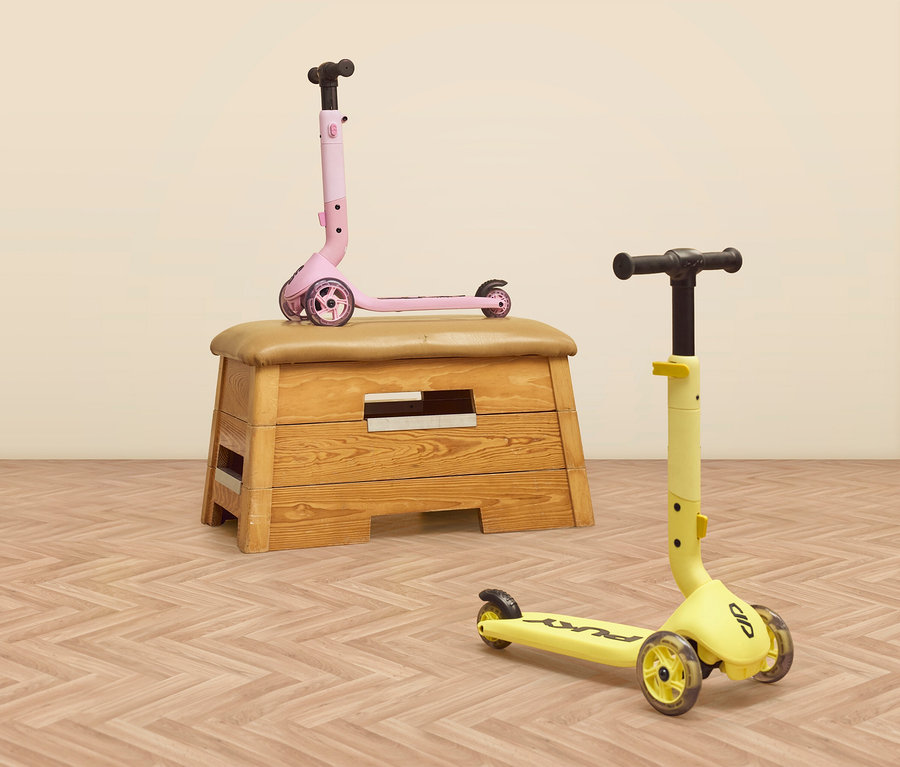 Ein rosa PUKY Roller PUSH steht auf einem Turnbock, ein gelber PUKY Roller PUSH steht auf einem Parkettboden.