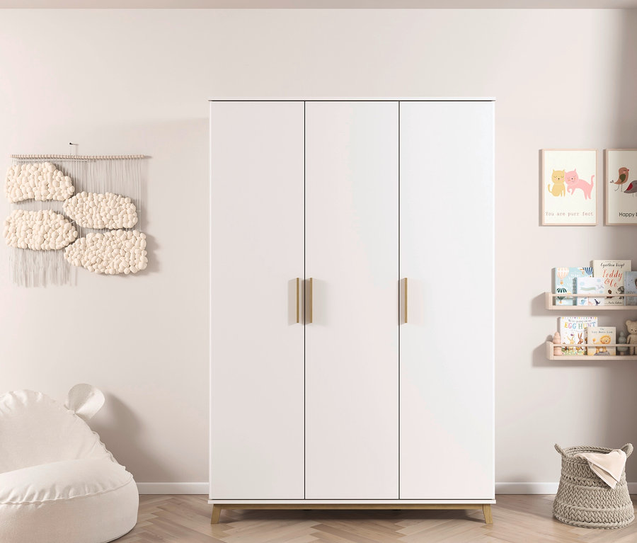 Weißer rauch Kleiderschrank »Carlsson« mit Drehtüren, 3-türig steht an einer Wand. An der Wand hängen ein Wandteppich und Regale mit Büchern.