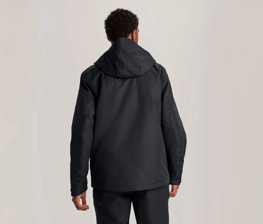 Eine Person von hinten gesehen, die eine dunkle Kapuzenjacke und eine dunkle Hose trägt.