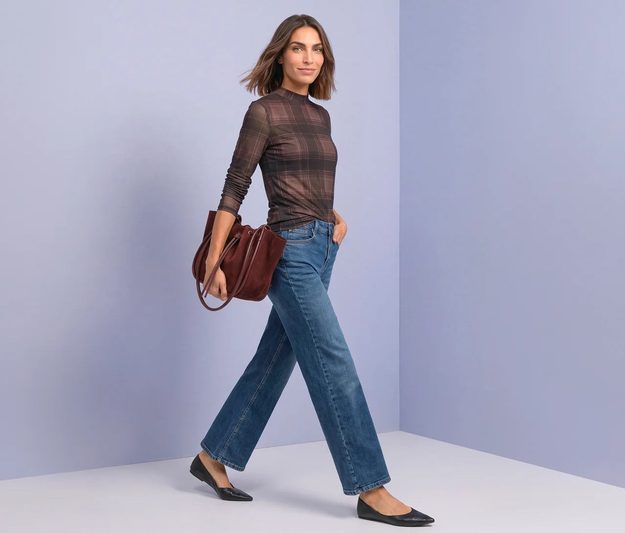 Frau geht, trägt ein braun kariertes Street One Mesh-Shirt, blaue weite Jeans, schwarze Ballerinas und eine bordeauxrote Tragetasche.