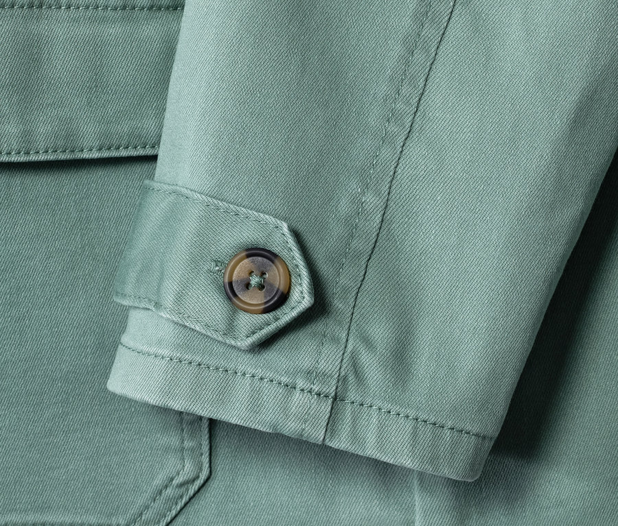 Detailaufnahme einer grünen Cargojacke mit braunem Knopf am Ärmel.
