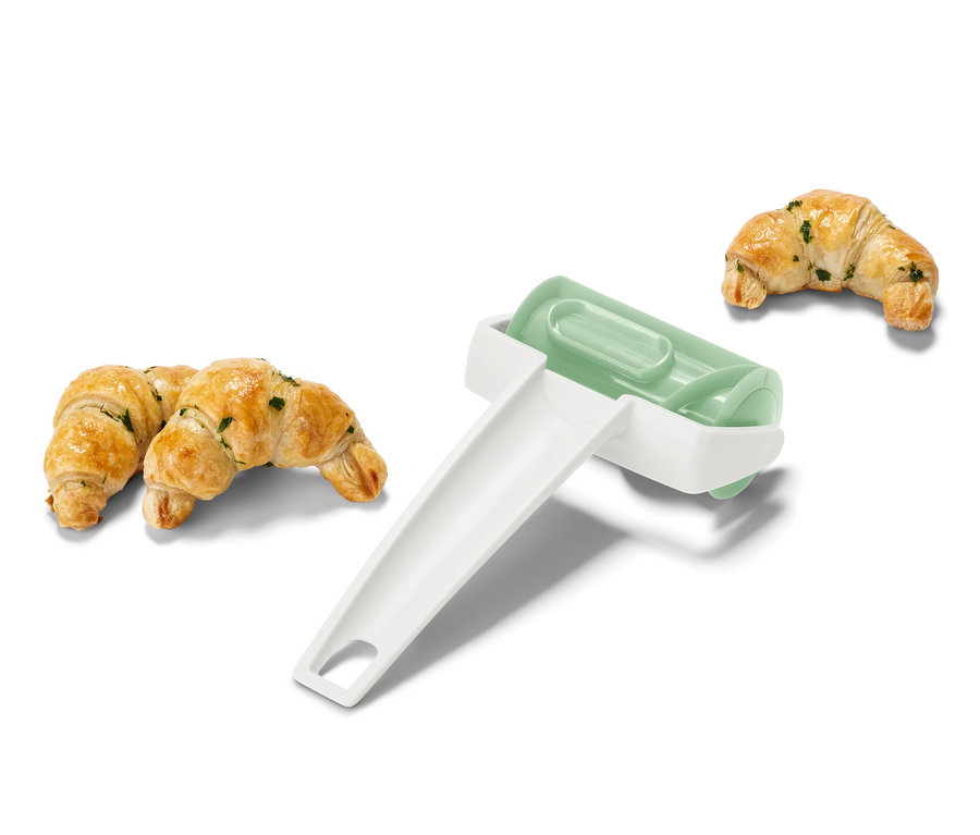 Zwei gebackene Croissants und ein Croissant-Roller.