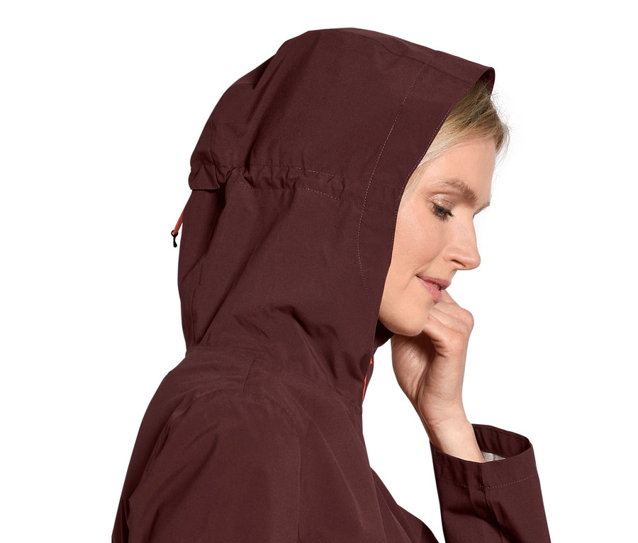 Blonde Frau trägt eine Funktionswanderjacke mit Kapuze.