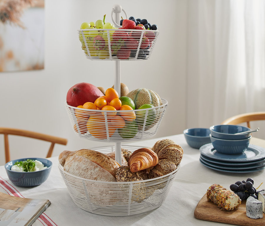 Eine dreistöckige Etagere mit Obst und Gebäck steht auf einem Tisch.