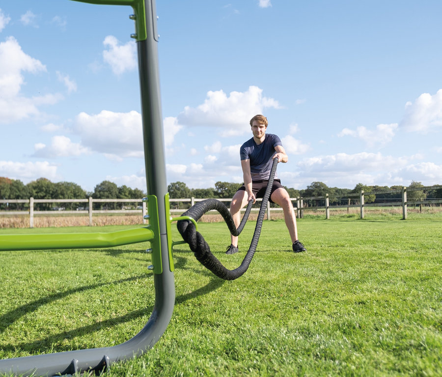 Mann trainiert draußen mit schwarzen Seilen am EXIT Klettergerüst MB220.