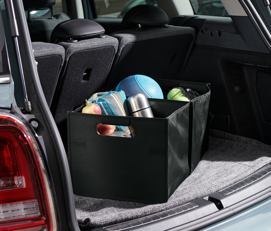 Eine Auto-Faltbox befindet sich im Kofferraum eines Autos. Im Inneren der Box befinden sich Obst, eine Decke, eine Thermoskanne und Bälle.