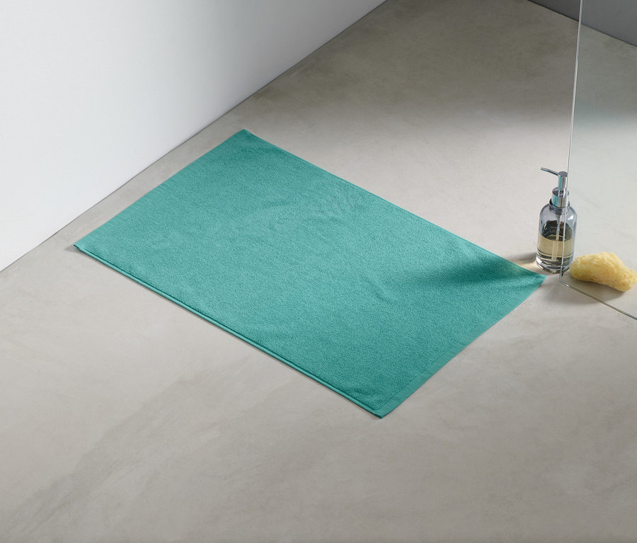 Ein aqua Duschvorleger liegt auf dem Boden neben einer Dusche.
