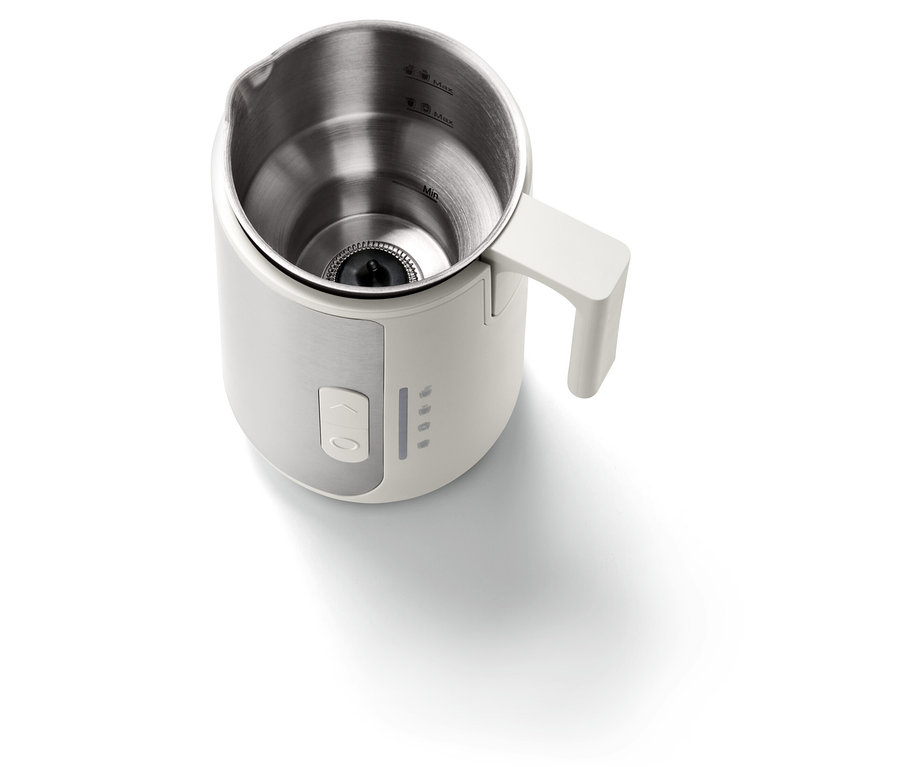 Nahaufnahme eines weißen Milchaufschäumers mit Edelstahlinnenseite und weißem Griff.