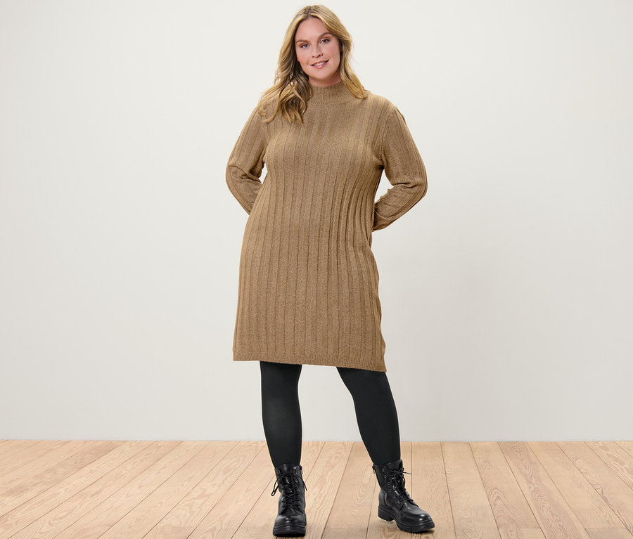 Frau posiert in einem gerippten Strickkleid mit Stehkragen, einer schwarzen Feinstrumpfhose (80 DEN) und schwarzen Stiefeln.