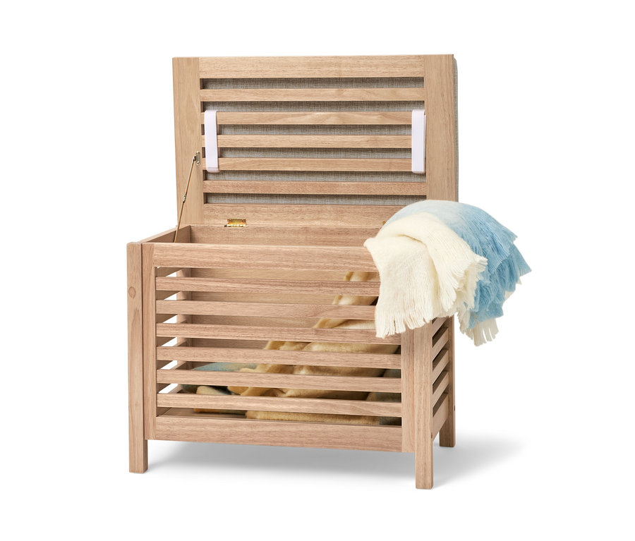 Geöffnete Massivholz-Sitztruhe mit Kissen und einer Decke darüber.