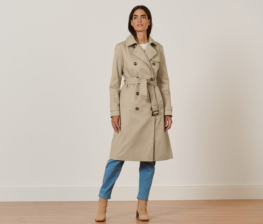 Frau posiert in beigem Trenchcoat.