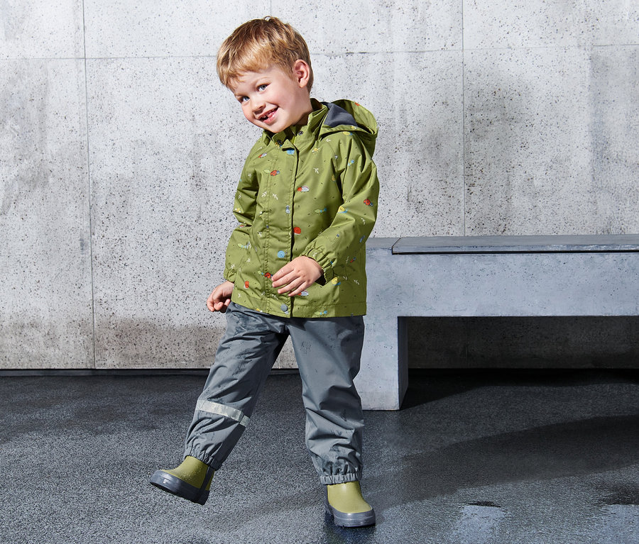 Junge trägt eine grüne Kleinkinder-Regenjacke mit Kapuze.