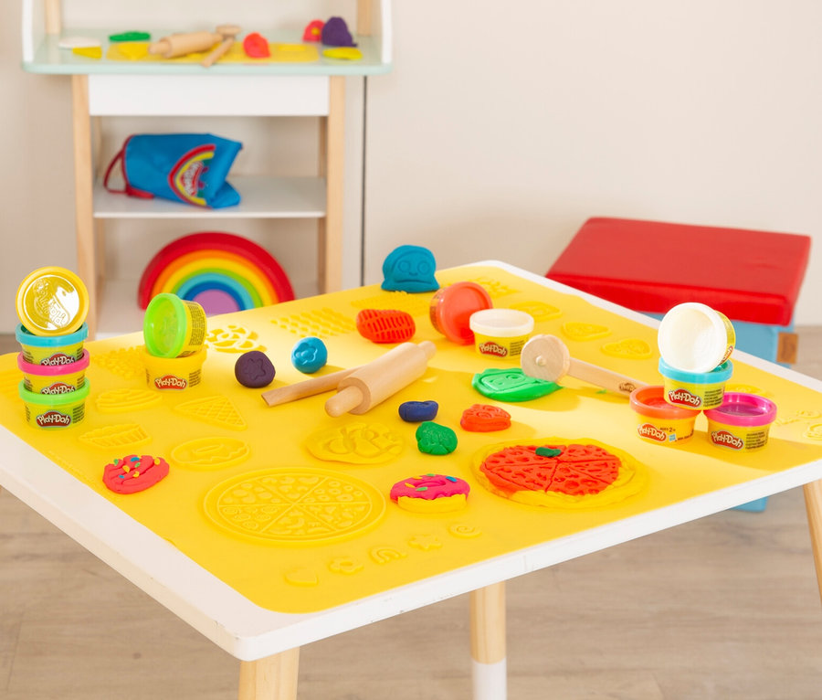 Gelbe Tischdecke mit Play-Doh Knete, Nudelholz und Förmchen.