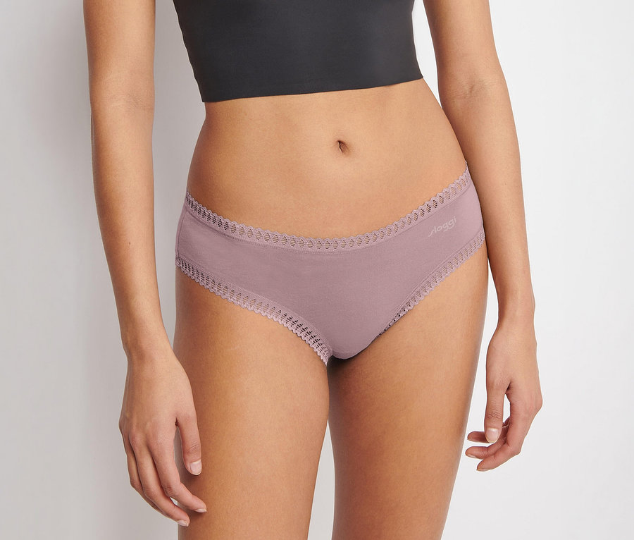 Eine Person trägt ein schwarzes Crop-Top und einen rosafarbenen sloggi GO Crush Hipster C3P Slip mit Spitzenbesatz.