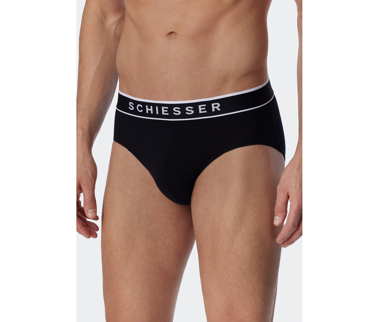 Mann trägt schwarze SCHIESSER Rio-Slips mit weißem Bund.