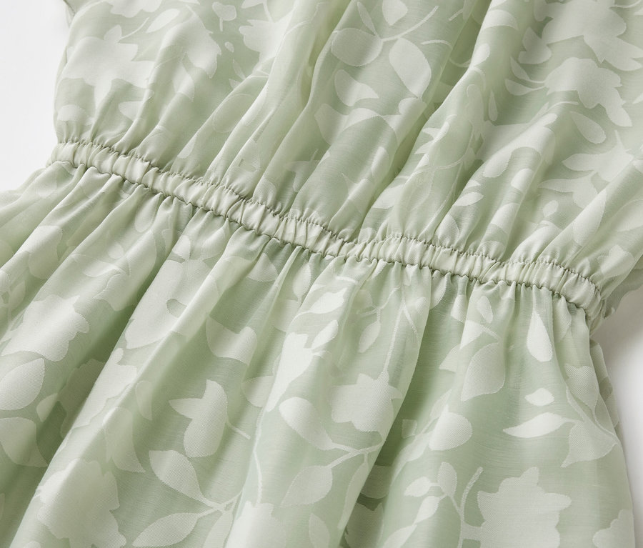 Detailaufnahme eines Kinder-Kleides mit Blattmuster und elastischer Taille.