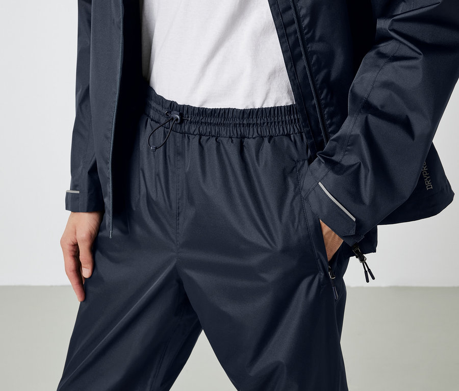 Person trägt dunkelblaue wasserdichte Hose und Jacke.