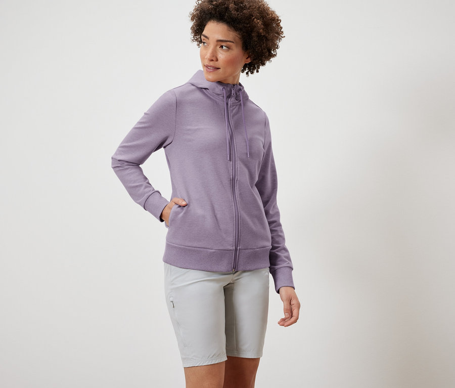 Frau trägt eine lila Sweatjacke und graue Shorts.