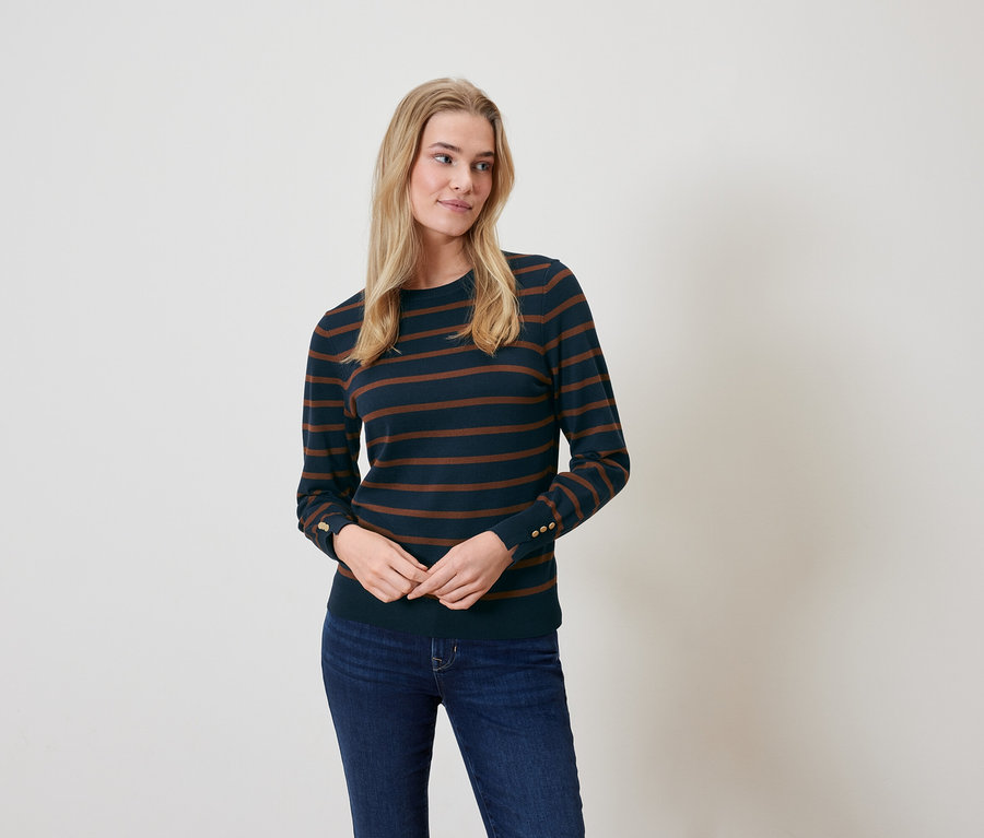 Blonde Frau posiert in einem gestreiften Pullover und Jeans.