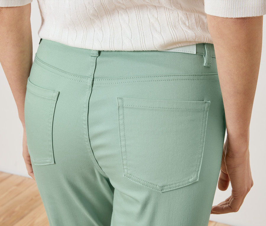 Nahaufnahme der Rückseite einer Frau, die hellgrüne Hosen und ein weißes Oberteil trägt.