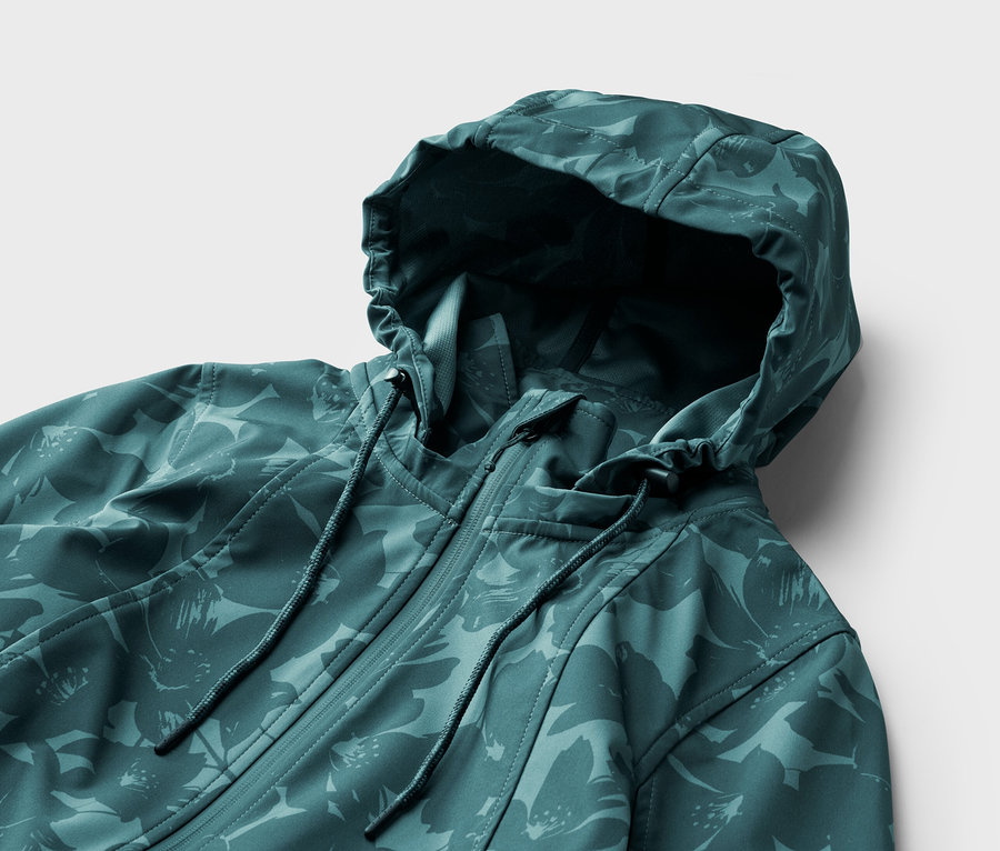Nahaufnahme einer petrolfarbenen, floral gemusterten Jacke mit Kapuze und Reißverschluss vor einem weißen Hintergrund.