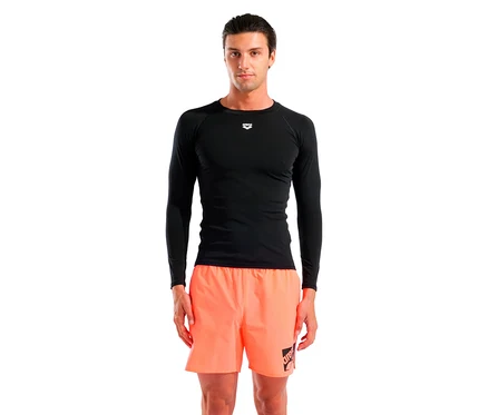 Mann steht, trägt ein schwarzes langärmeliges Shirt und orangefarbene Shorts.