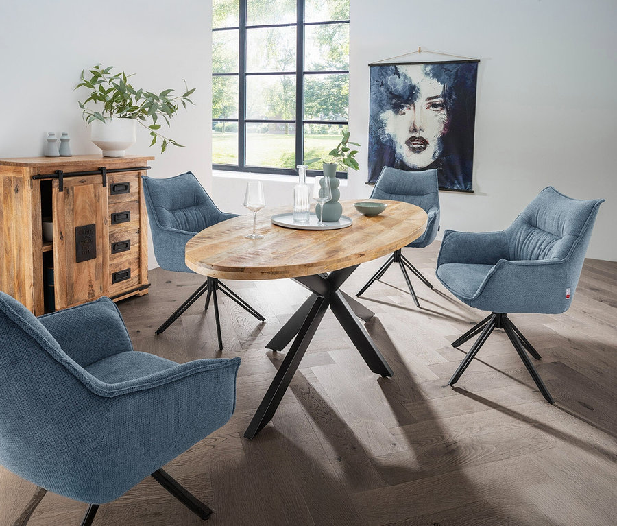 Esstisch mit vier blauen, drehbaren DeVries »Ginosa« Sesseln. Auf dem Tisch stehen Gläser und Dekoration.