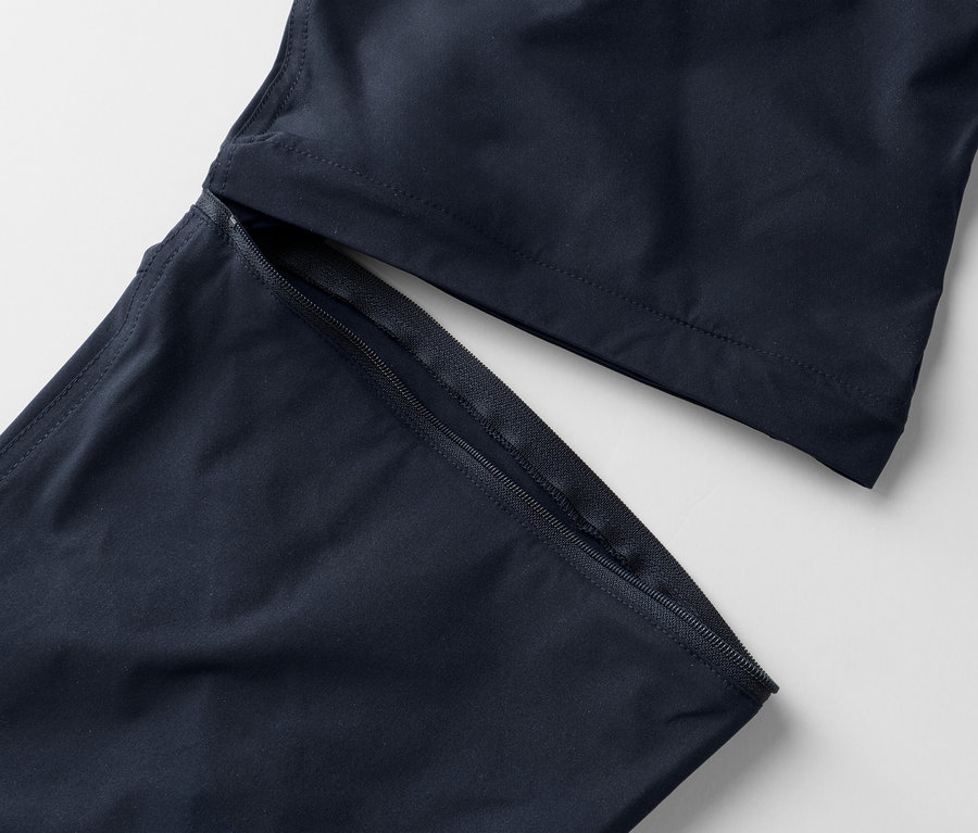 Nahaufnahme von marineblauen Hosenbeinen mit freiliegendem Reißverschluss auf weißem Hintergrund.