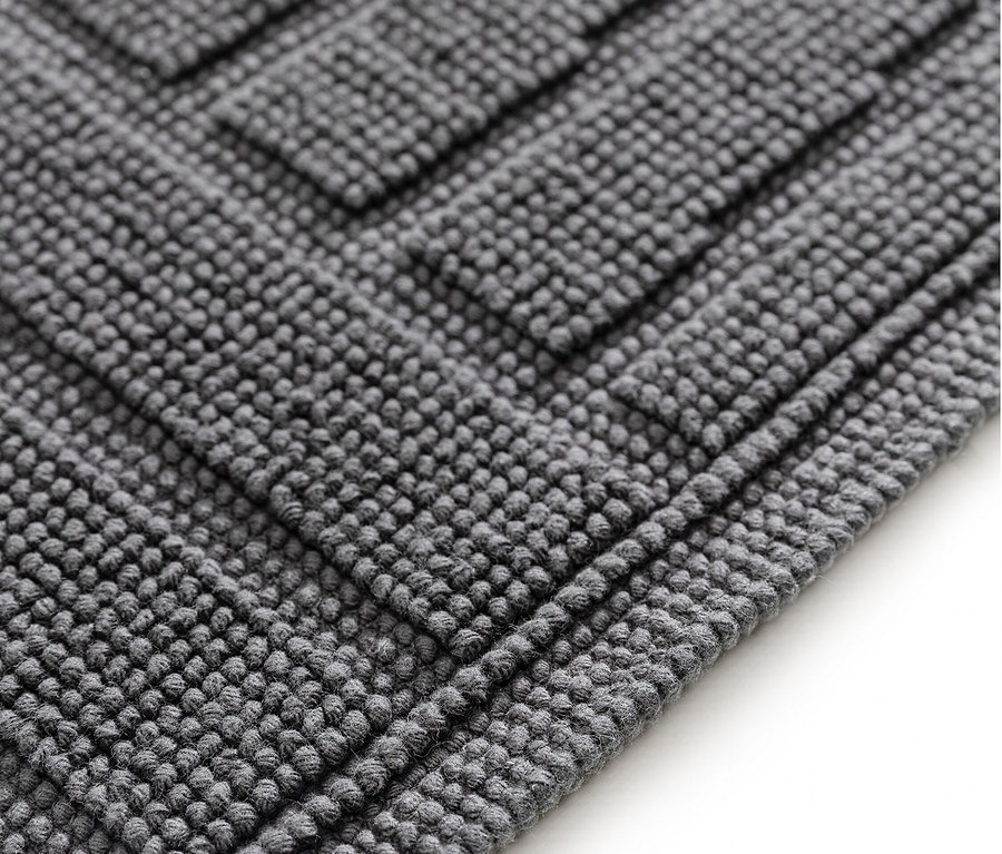 Nahaufnahme eines grauen Badvorlegers mit erhabenem, geometrischem Muster.