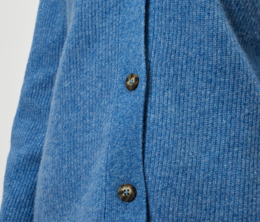 Nahaufnahme einer blauen Strickjacke mit braunen Knöpfen.