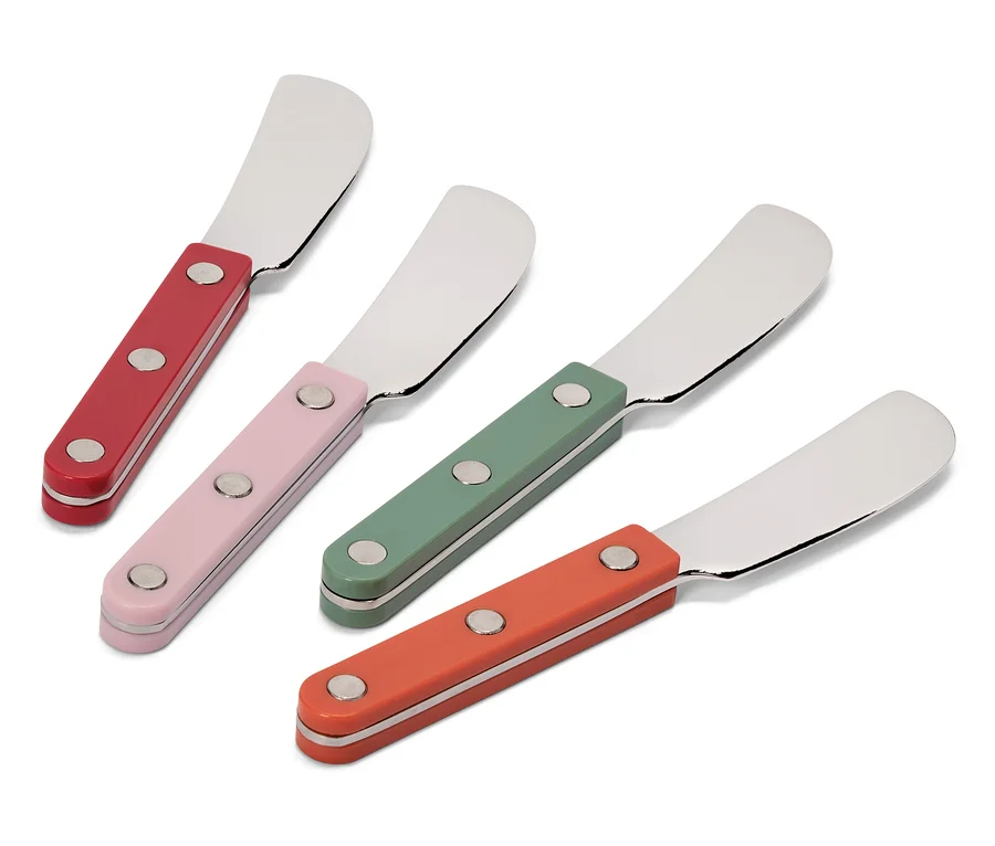 Vier Buttermesser mit farbigen Griffen in Rot, Rosa, Grün und Orange liegen diagonal auf weißem Grund.