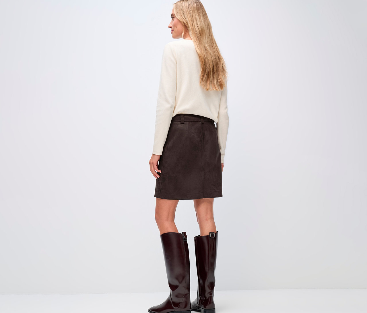 Frau von hinten, trägt einen cremefarbenen Pullover und einen braunen Street One Veloursrock, dazu braune Stiefel.