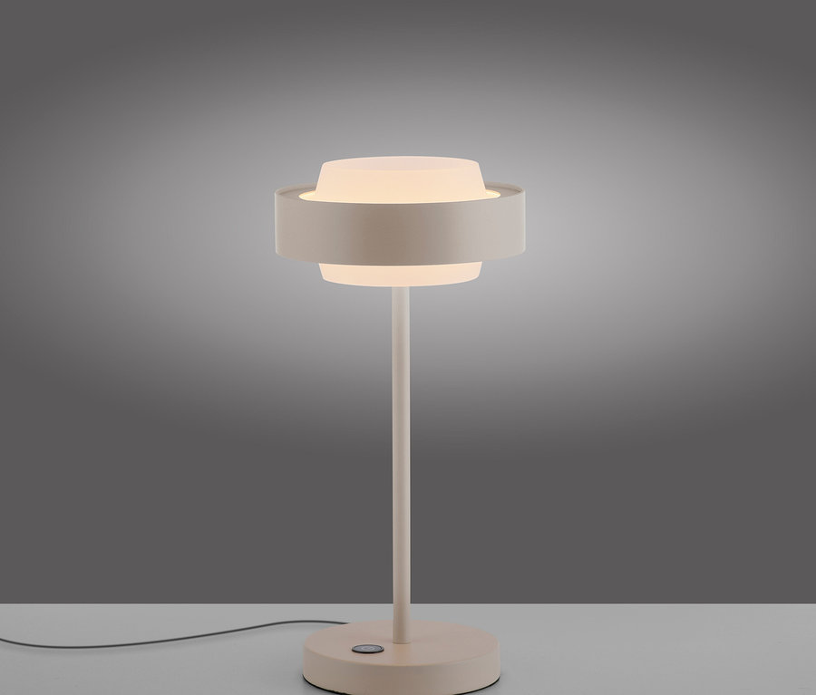 Helle, moderne Tischlampe mit rundem Fuß und zwei übereinanderliegenden, runden Schirmen, die leuchten, auf grauem Hintergrund.