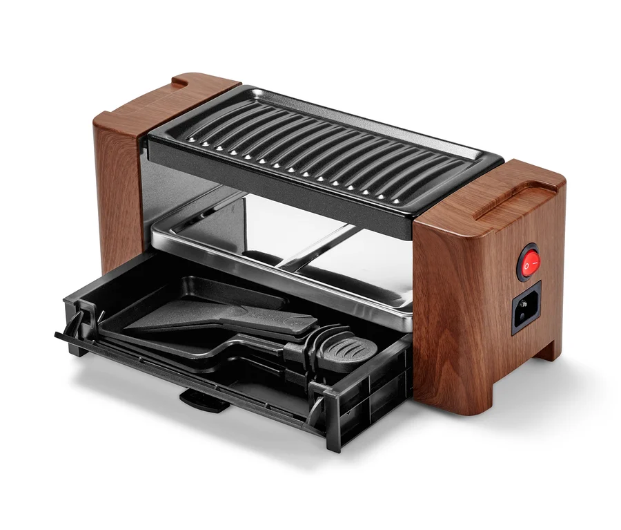 Detailaufnahme eines Raclette-Grills für 2 Personen mit geöffneter Schublade und Zubehör.