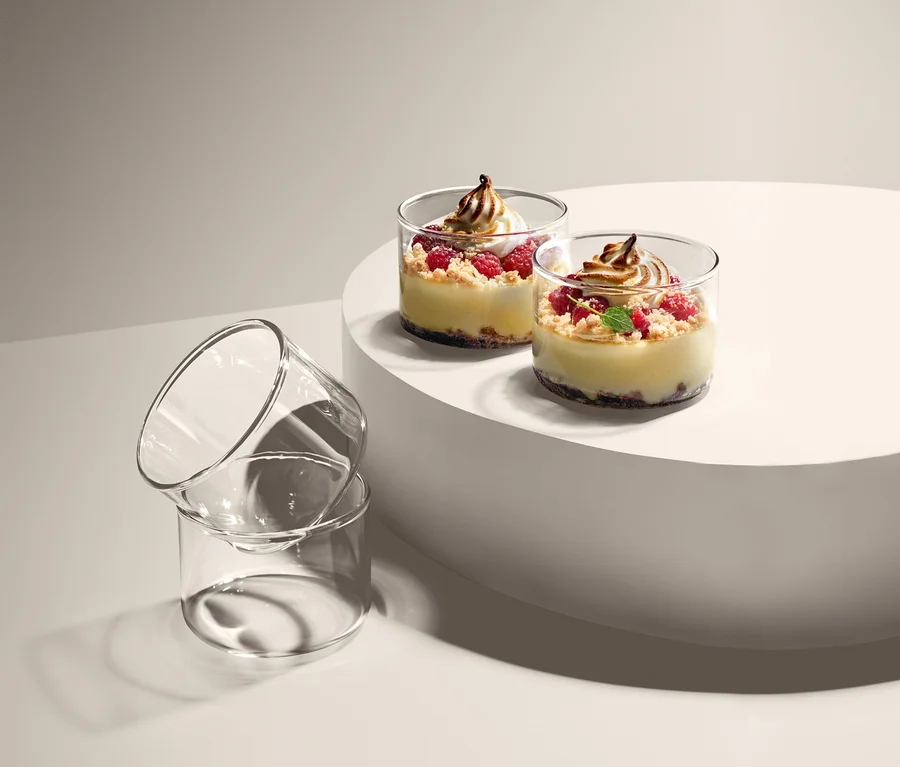 Zwei Desserts in 4 Portions- und Ofengläser auf einem weißen Sockel, daneben zwei leere 4 Portions- und Ofengläser gestapelt.