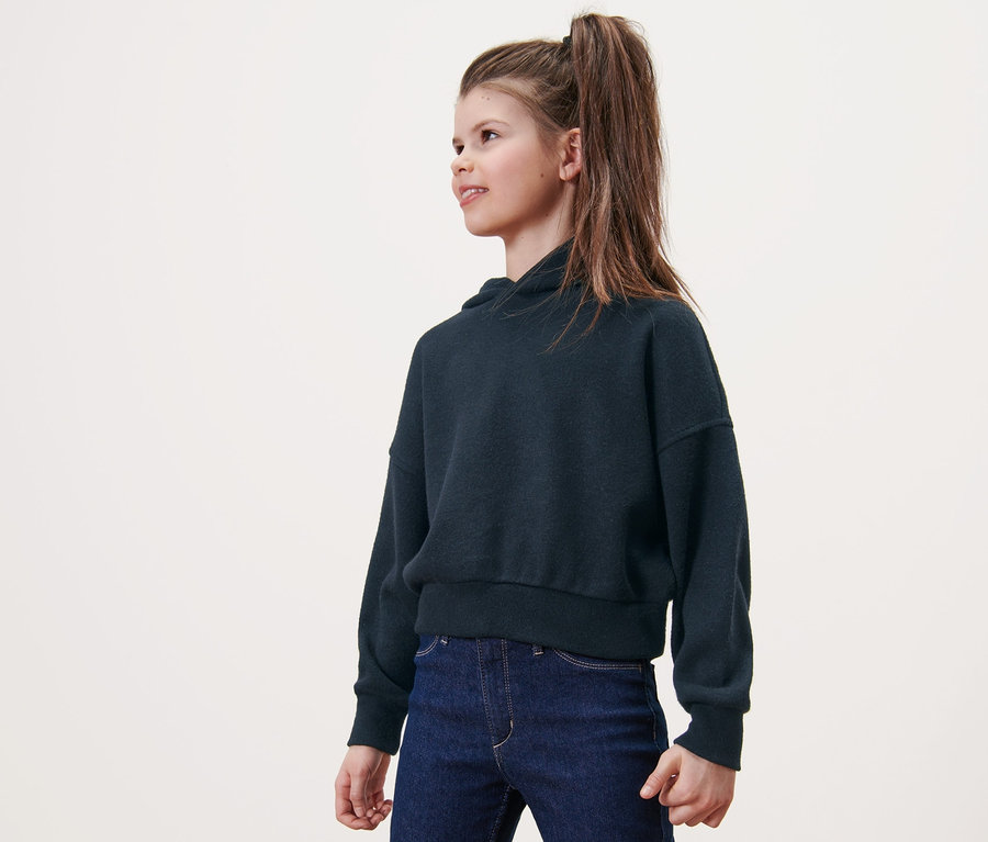 Mädchen trägt Kinder-Strickhoodie und Jeans.