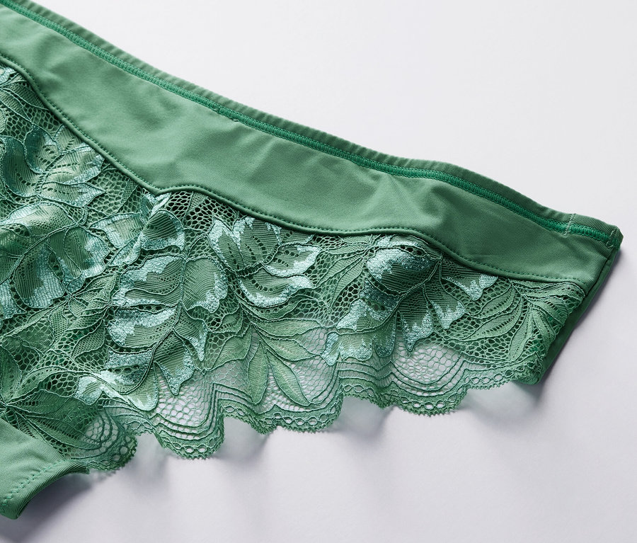 Detailaufnahme eines grünen 4 Brazilslips mit Blumenspitze auf weißem Hintergrund.