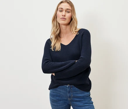 Frau posiert in dunkelblauem Strickpullover.