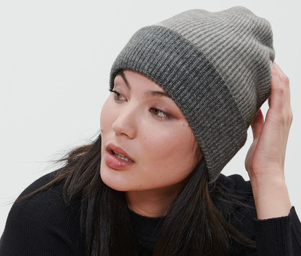 Frau sitzt auf einem Stuhl und trägt eine graue Strickmütze.