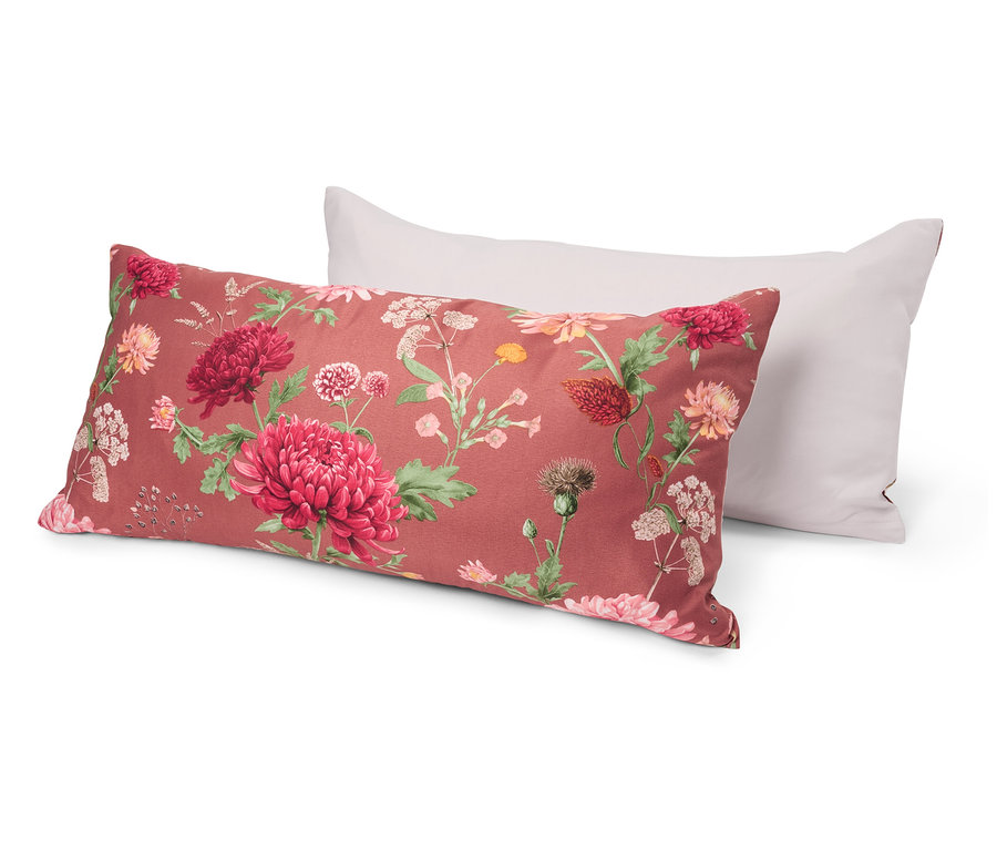 Zwei Kissen liegen übereinander. Das untere Kissen hat ein florales Muster mit roten und rosa Blüten auf rotem Grund. Das obere Kissen ist weiß.