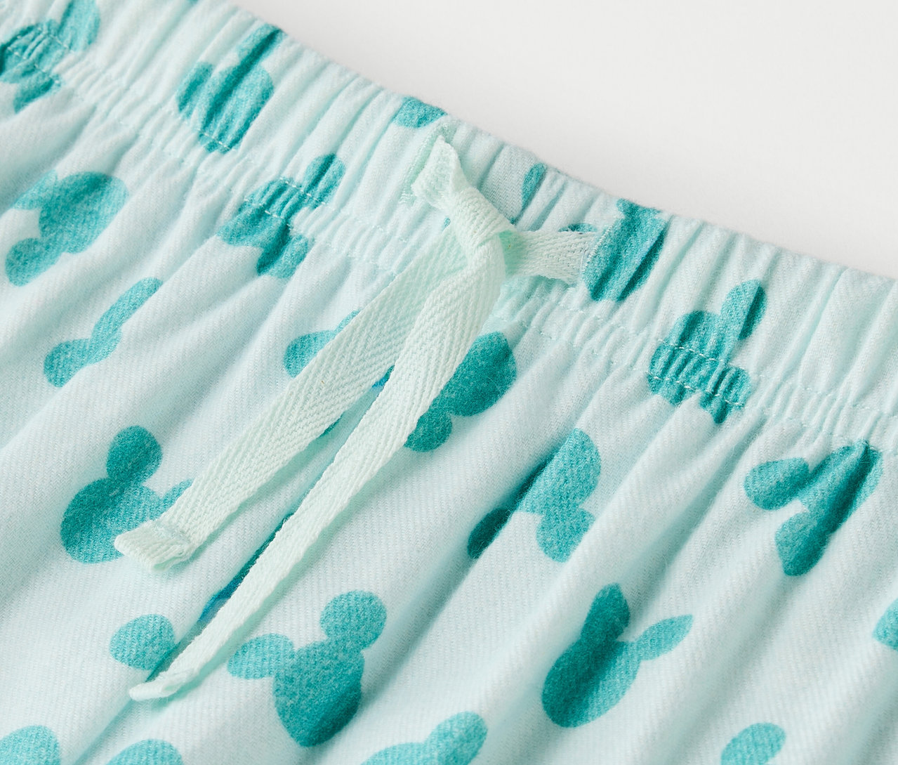Detail einer hellblauen Hose mit Mickey Mouse-Print und Kordelzug.